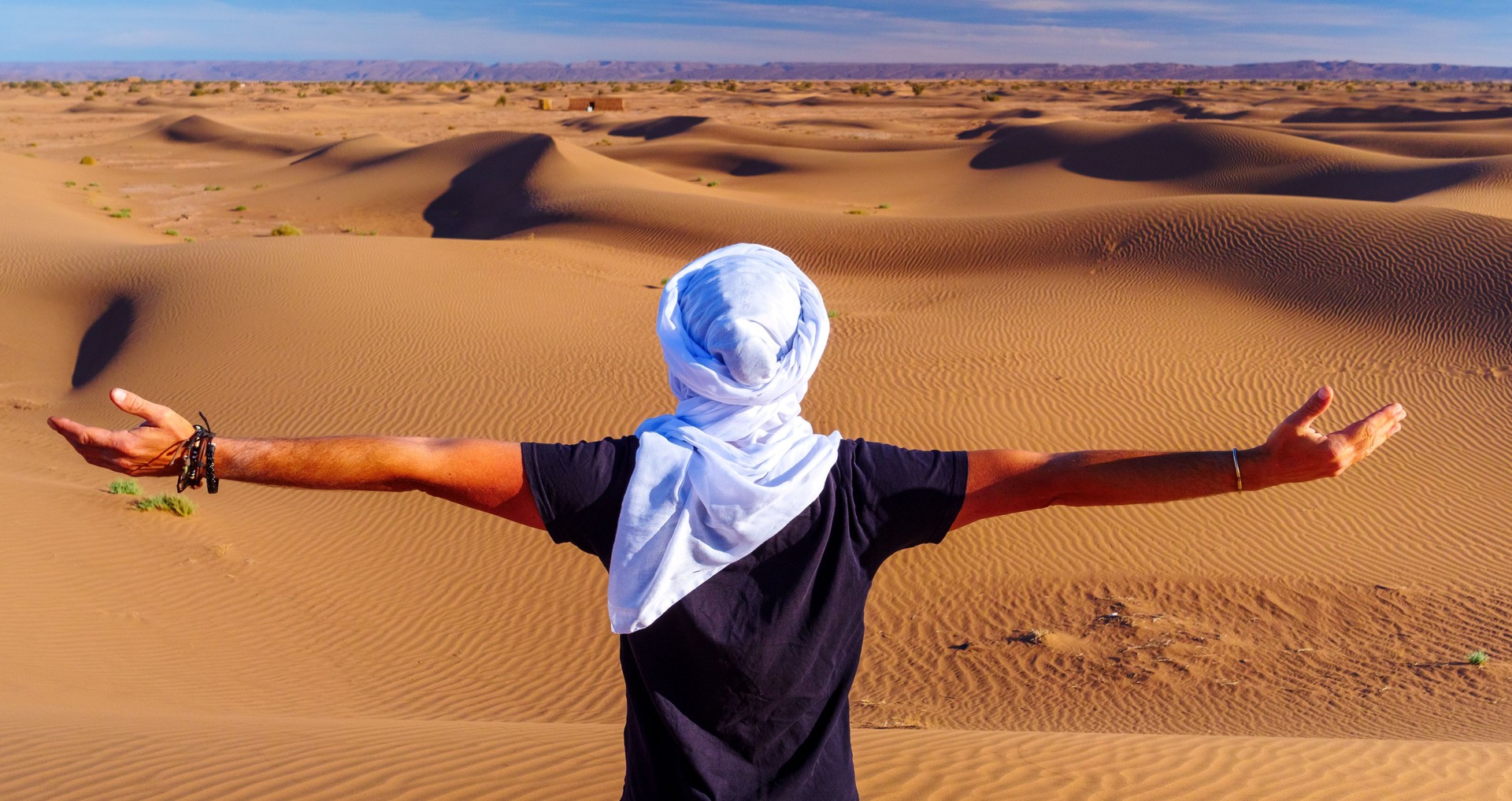 Man with arms outstretched in the desert- Sahara in Morocco