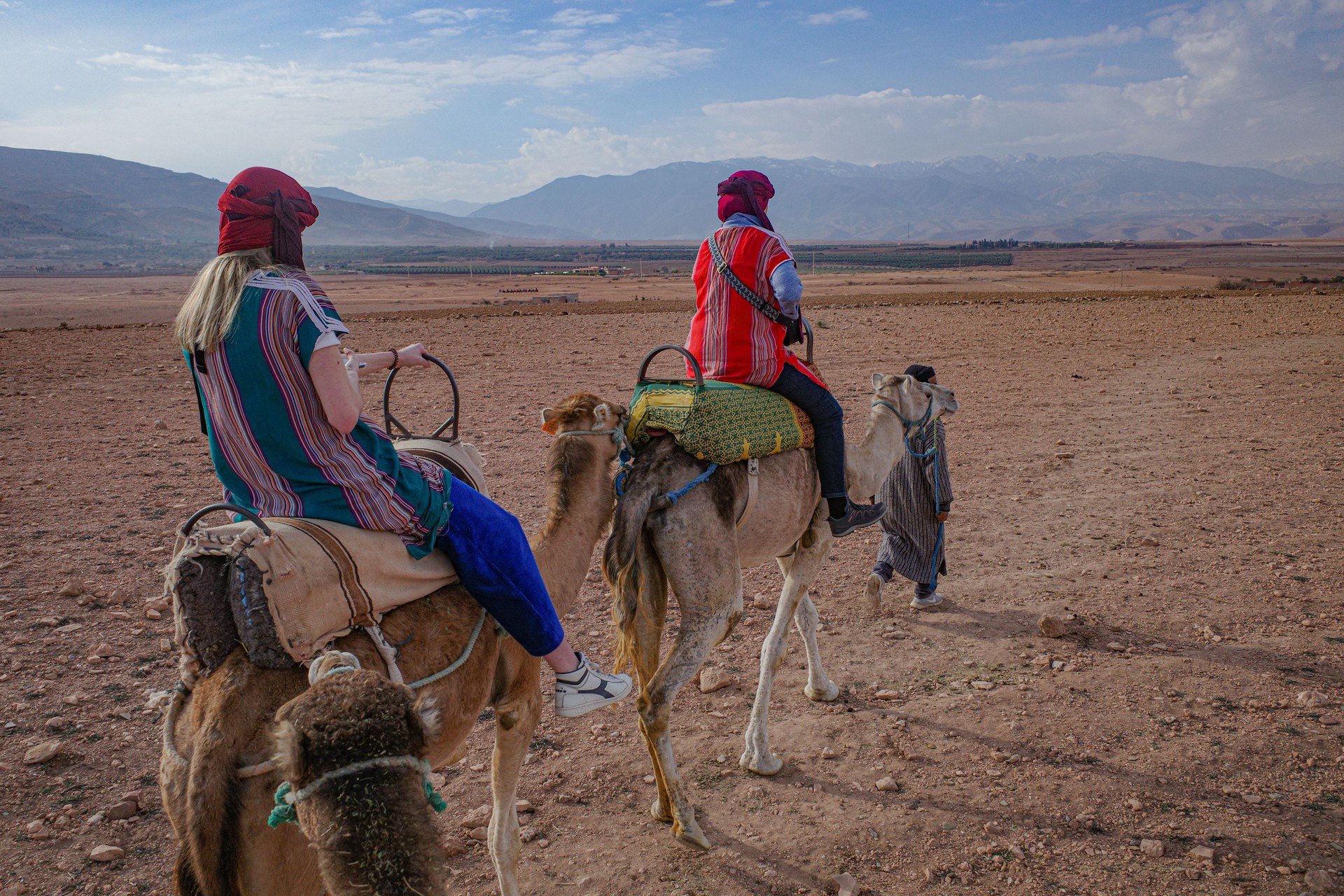 Marrakech, Morocco - Feb 22, 2023: Tourists ride Dromedary camels through the Agafay desert