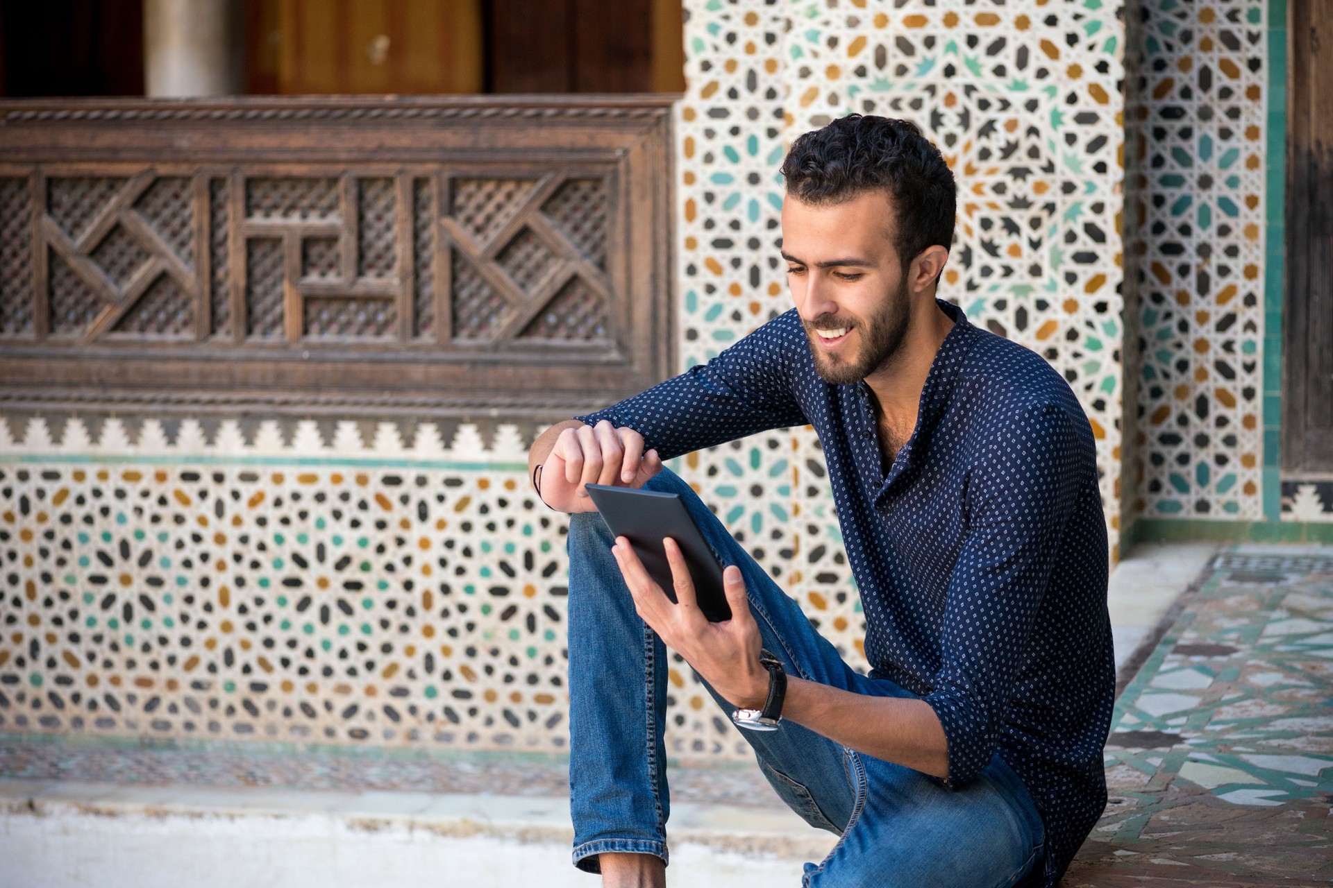 Young Muslim man working on tablet in traditional Arabian ambient