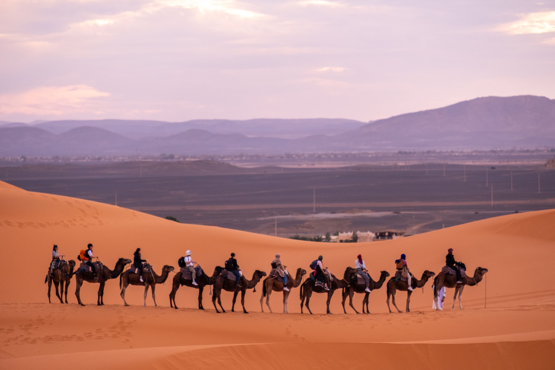 Tourists take a camel ride across the sands of the Sahara. Camel rides are a major tourist attraction in the Sahara in Merzouga, Morocco.