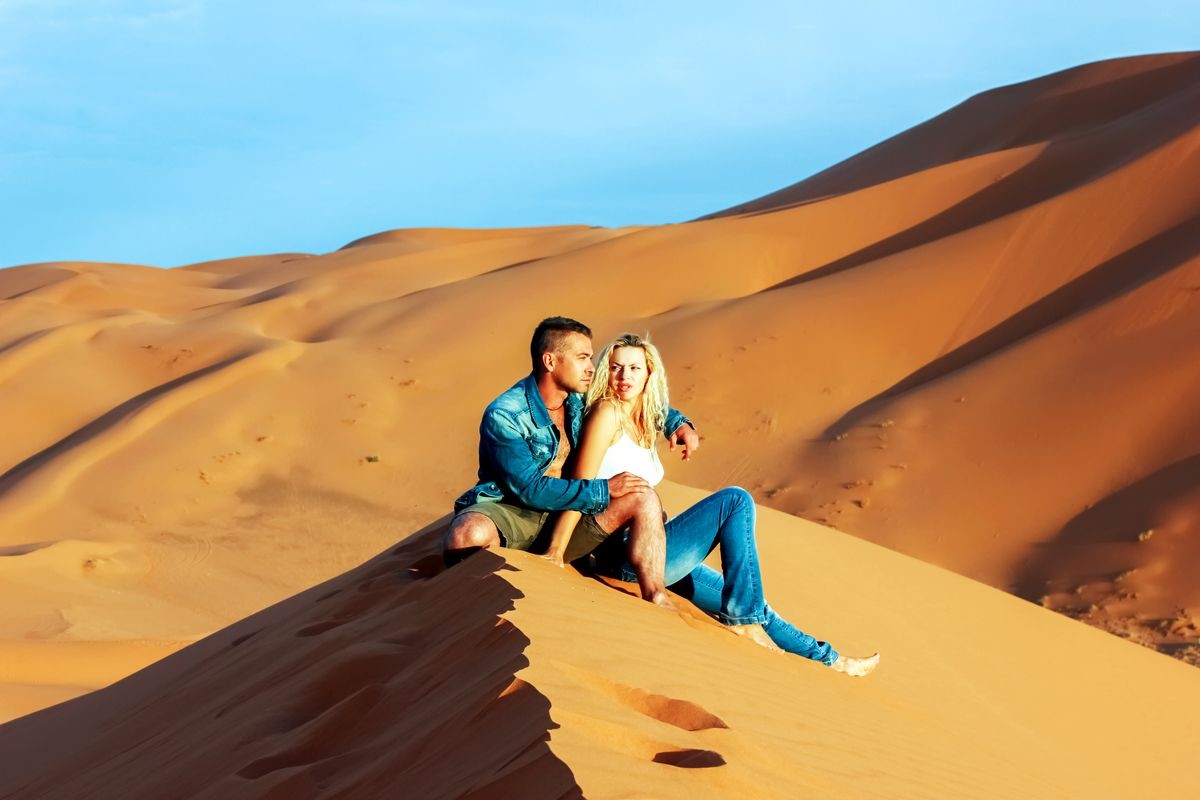 Guy and girl on the sand dunes in the Sahara Desert.